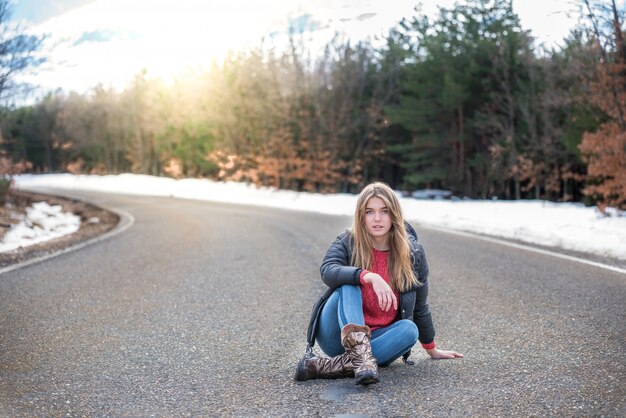 Foto jovens bonitas mulher em uma estrada com neve no inverno