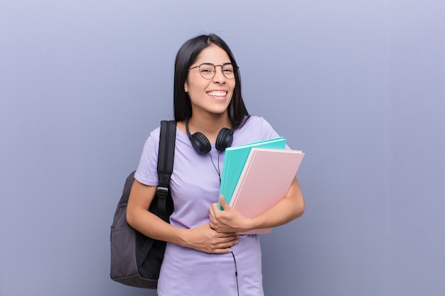 Jovens bonitas mulher estudante latina contra parede cinza