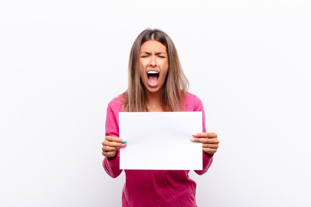 Jovens bonitas mulher gritando agressivamente, parecendo muito zangado, frustrado, indignado ou irritado, gritando sem segurar um cartaz