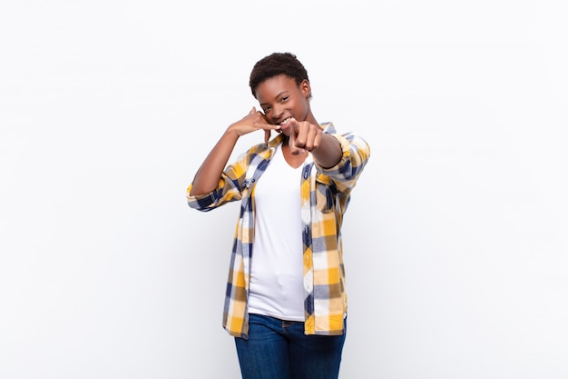 Jovens bonitas mulher negra sorrindo alegremente e apontando ao fazer uma chamada você mais tarde gesto, falando no telefone