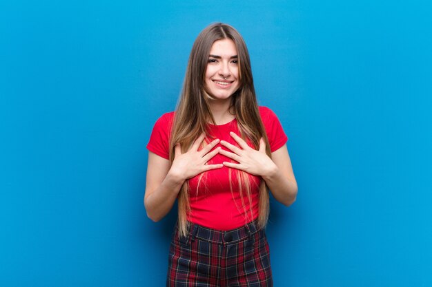 Jovens bonitas mulher olhando feliz, surpreso, orgulhoso e animado, apontando para si mesmo sobre parede azul