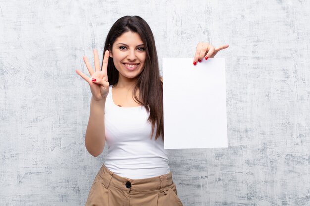 Foto jovens bonitas mulher segurando uma folha de papel contra a parede de cimento grunge