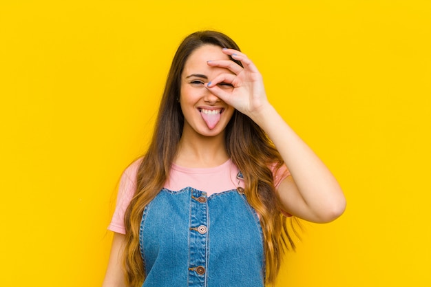 Jovens bonitas mulher sorrindo alegremente com cara engraçada, brincando e olhando pelo olho mágico, espionando segredos