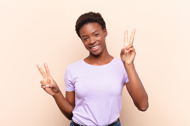 Jovens bonitas mulher sorrindo e olhando feliz, amigável e satisfeito, gesticulando vitória ou paz com as duas mãos