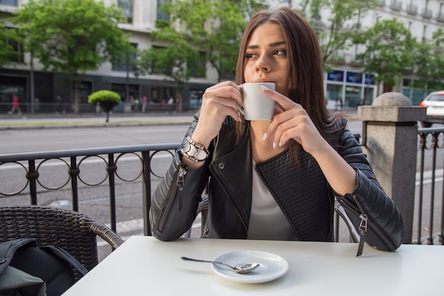 Jovens bonitas mulher tomando café em um terraço na rua.