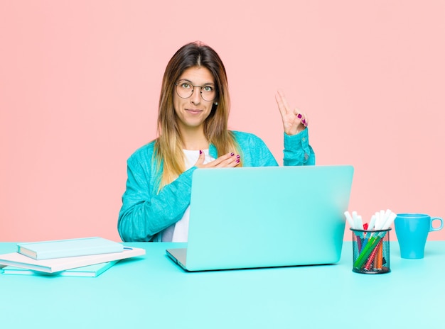 Jovens bonitas mulher trabalhando com um laptop olhando feliz, confiante e confiável, sorrindo e mostrando sinal de vitória, com uma atitude positiva