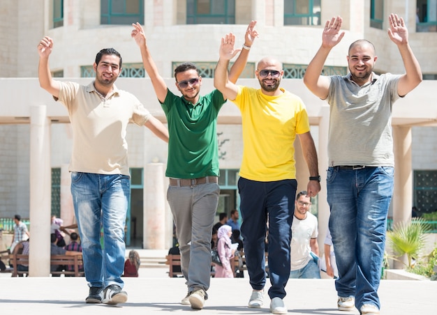 Jovens caminhando juntos com os braços para cima