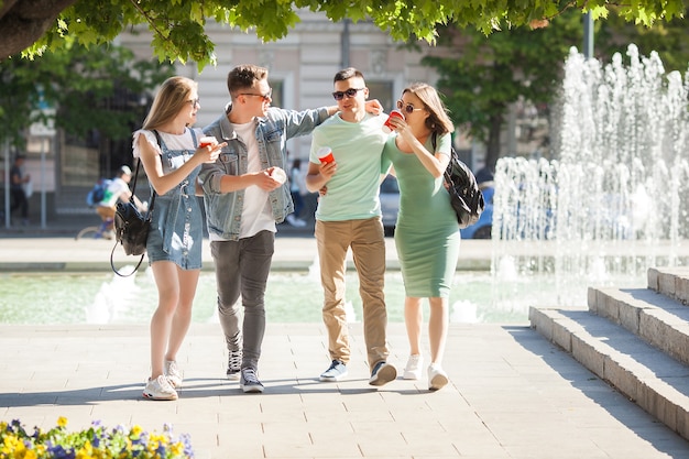 Jovens caminhando pela cidade. Amigos elegantes juntos se divertindo. Grupo de pessoas tomando café e conversando.