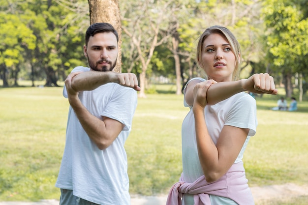 Jovens casais jogando yoga no parque. Casais estão se exercitando no parque.