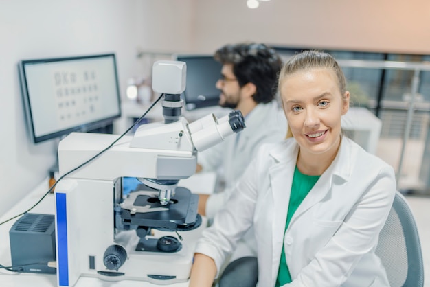 Jovens cientistas em uniforme branco, trabalhando em laboratório