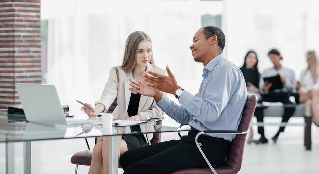 Jovens colegas de trabalho conversando atrás de uma mesa