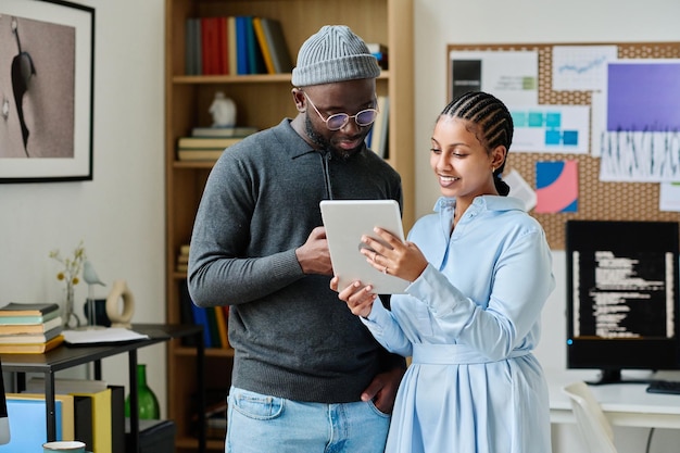 Jovens colegas discutindo a apresentação no tablet pc juntos enquanto estão no escritório