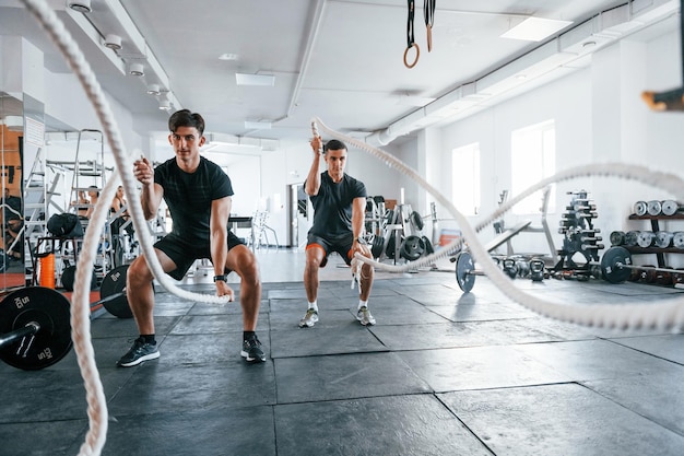 Jovens com formas corporais esportivas fazendo crossfit usando nós