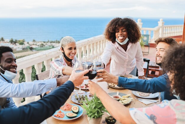 Jovens comemorando com vinho e usando máscaras protetoras