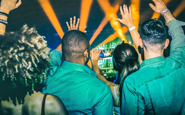 Foto jovens dançando na boate mãos para cima nas luzes do show de laser na boate depois da festa