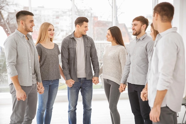 Jovens de mãos dadas durante terapia de grupo dentro de casa