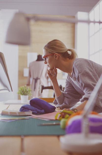 Foto jovens designers de moda femininas atraentes inclinando-se na mesa de escritório trabalhando com um laptop