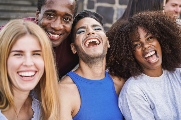 Jovens diversos se divertindo ao ar livre rindo juntos - Foco no rosto masculino gay