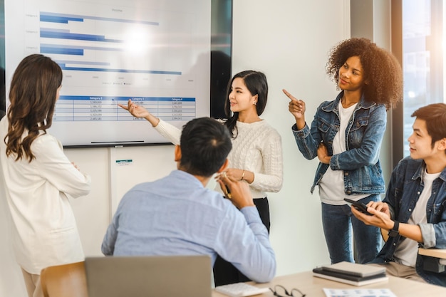 Jovens e bem sucedidos empresários asiáticos de raça mista trabalhando em projeto juntos sentados à mesa na sala de reuniões