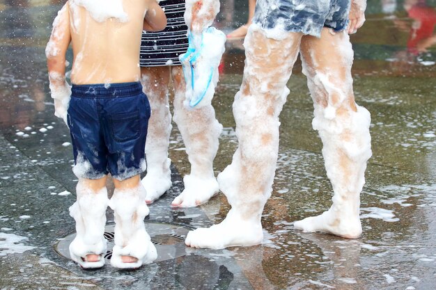 Jovens em espuma com sabão caminhando em uma estrada molhada