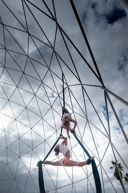 Jovens em forma de corpo lindo, garotas fazendo exercícios acrobatas de circo suspensos no ar com cordas