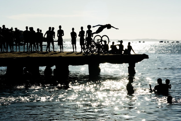 jovens em silhueta são vistos se divertindo e pulando da ponte Crush na cidade de Salvador Bahia