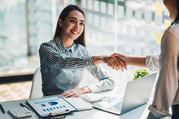 Foto jovens empresários asiáticos apertando as mãos no escritório terminando a reunião bem-sucedida