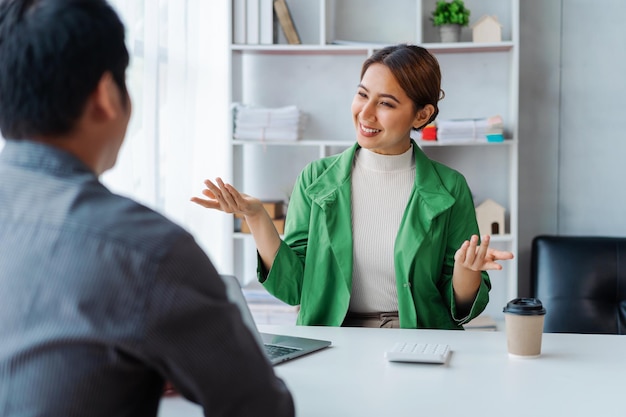 Jovens empresários asiáticos e mulheres conversando discutindo o trabalho no escritório moderno quando sentados à mesa