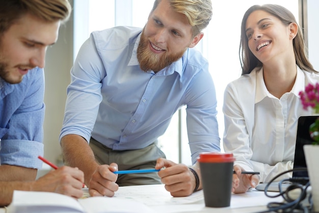 Jovens empresários confiantes discutindo algo enquanto olham para a planta no escritório, equipe de arquitetura.