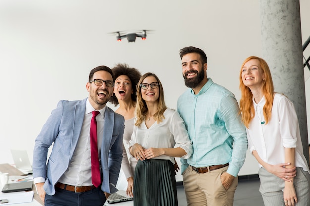 Jovens empresários feliz deixando a câmera do zangão voar sobre o escritório e se divertindo