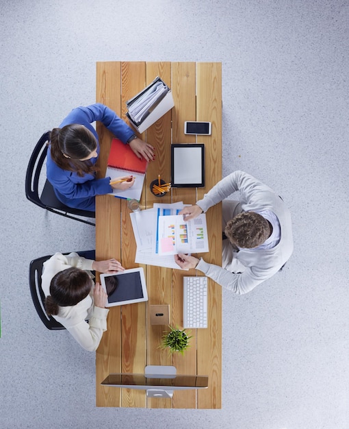 Jovens empresários sentados à mesa trabalhando juntos usando computador portátil