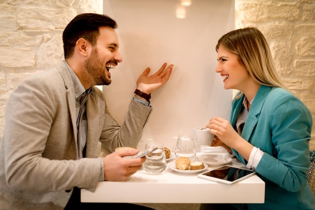 Jovens empresários sorridentes em uma pausa em um café. Eles estão bebendo café e conversando com um sorriso.