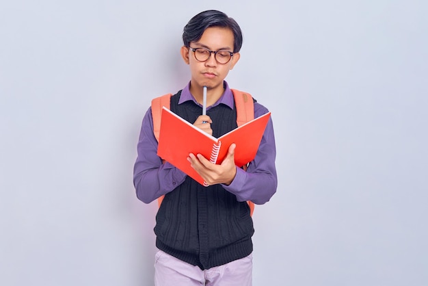 Jovens estudantes asiáticos concentrados com mochilas em roupas casuais gostam de ler livros e pensar na pergunta e resposta isoladas em fundo cinza