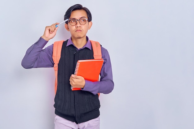 Jovens estudantes asiáticos concentrados com mochilas segurando cadernos e pensando em algo isolado em fundo cinza Educação no conceito de faculdade universitária do ensino médio