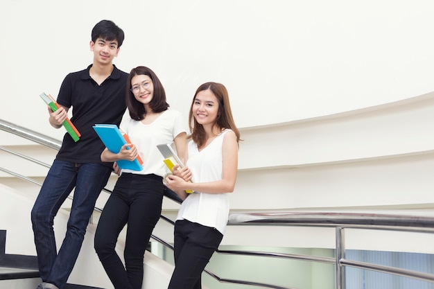 Jovens estudantes em pé com segurando livros na biblioteca.