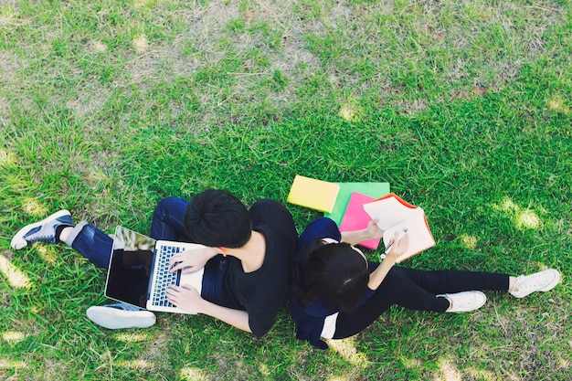 Jovens estudantes localização na grama verde e leitura