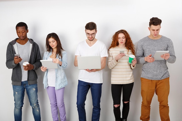 Foto jovens estudantes multiétnicos com aparelhos, dentro de casa. tecnologias modernas de educação.