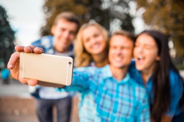 Jovens estudantes tomando selfie no parque juntos