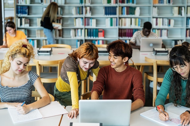 Jovens estudantes universitários usando laptop e estudando com livros na biblioteca Conceito de educação escolar