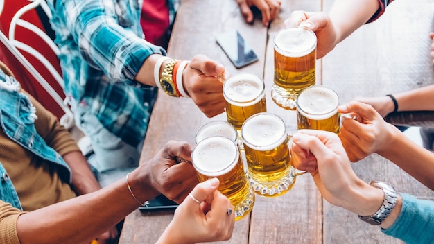 Jovens felizes e diversos celebrando juntos e brindando cervejas