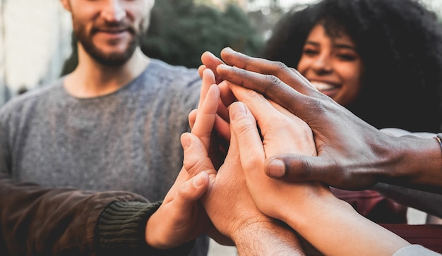 Jovens felizes empilhando as mãos ao ar livre