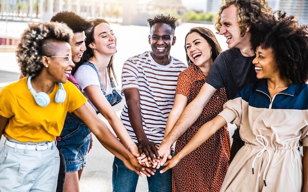 Jovens felizes multirraciais colocando as mãos uns sobre os outros