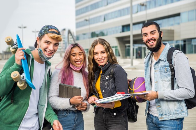 Jovens felizes se encontrando ao ar livre e usando máscaras durante a pandemia covid19