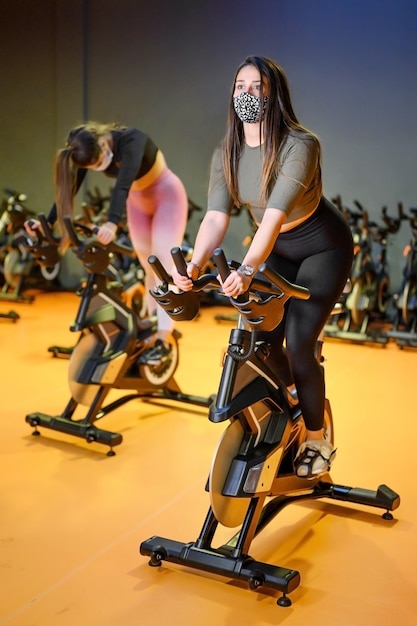 Jovens girando no ginásio de fitness com máscara protetora durante o surto de coronavírus.