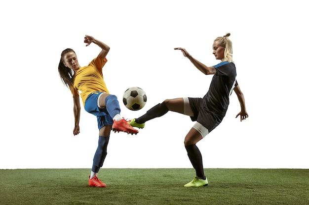 Jovens jogadoras de futebol ou futebol feminino com cabelo comprido em roupas esportivas e botas de treinamento em fundo branco. Conceito de estilo de vida saudável, esporte profissional, movimento, movimento. Lute pelo gol.