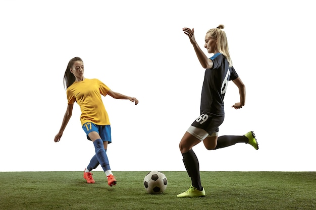 Jovens jogadoras de futebol ou futebol feminino com cabelo comprido em roupas esportivas e botas, treinando em fundo branco. Conceito de estilo de vida saudável, esporte profissional, movimento, movimento. Lute pelo gol.