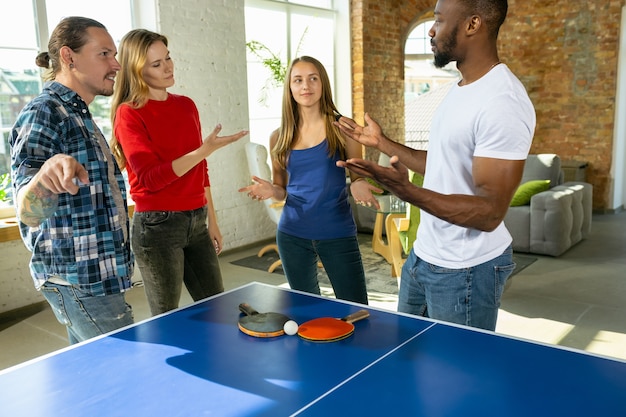 Jovens jogando tênis de mesa no local de trabalho, se divertindo