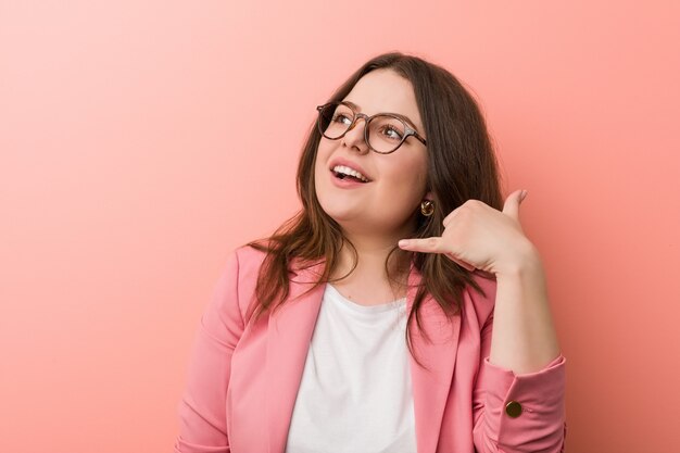 Foto jovens mais tamanho mulher caucasiana, mostrando um gesto de chamada de telefone móvel com os dedos.