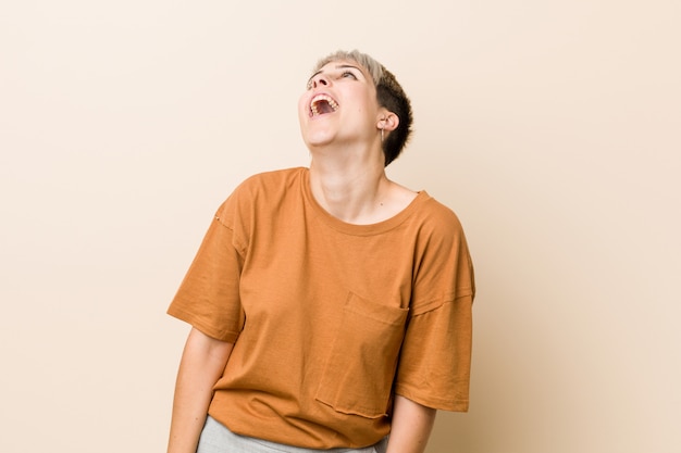 Jovens mais tamanho mulher com cabelo curto relaxado e feliz rindo, pescoço esticado, mostrando os dentes.