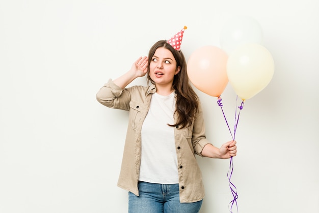 Jovens mais tamanho mulher curvilínea comemorando um aniversário tentando ouvir uma fofoca.